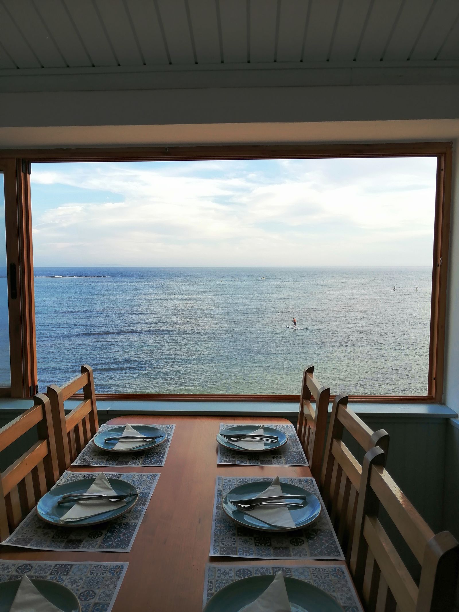 Wooden dining table and chairs overlooking the water