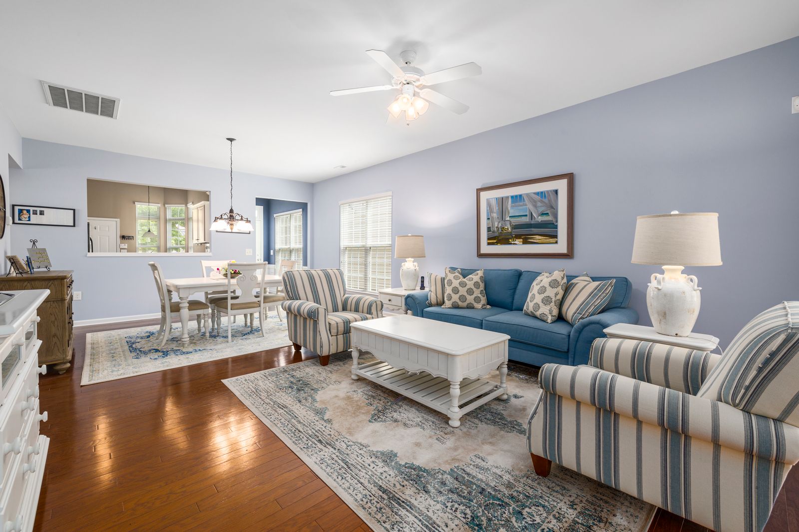 Elegant coastal living room with blue sofas and striped accent chairs