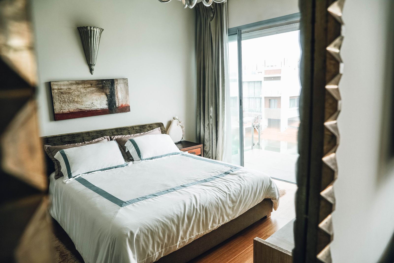 Sunlit bedroom with crisp linens, a framed print and neutral walls