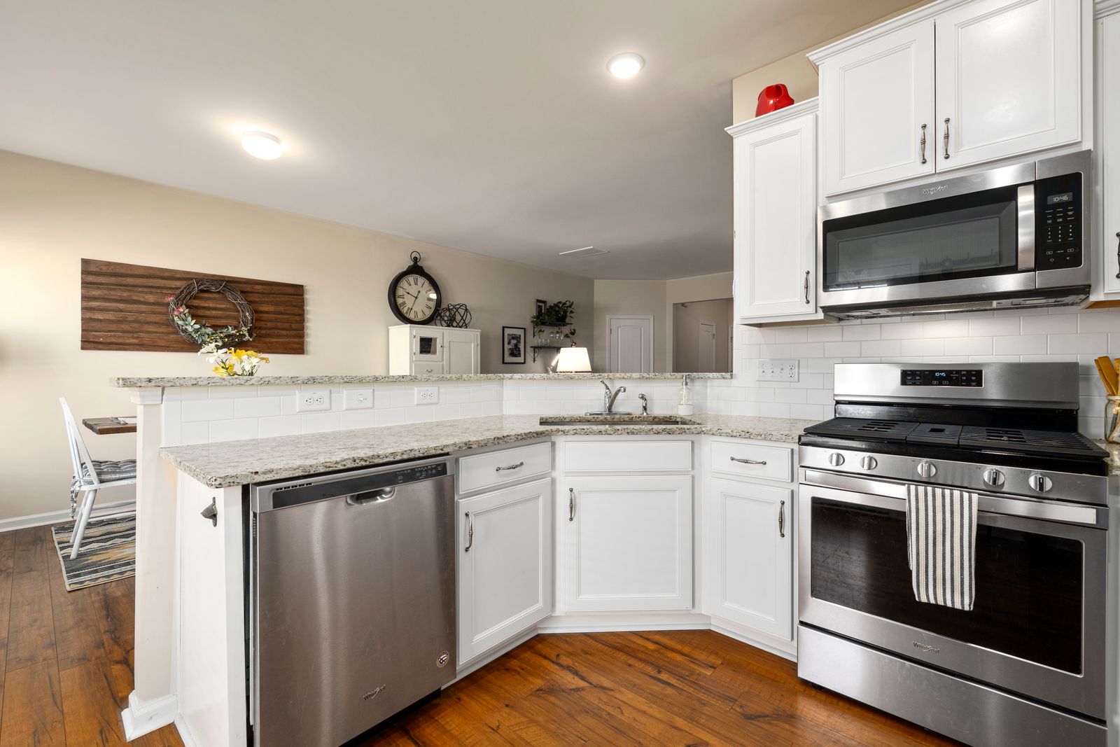 White kitchen cabinets with a marble counter and hardwood floor