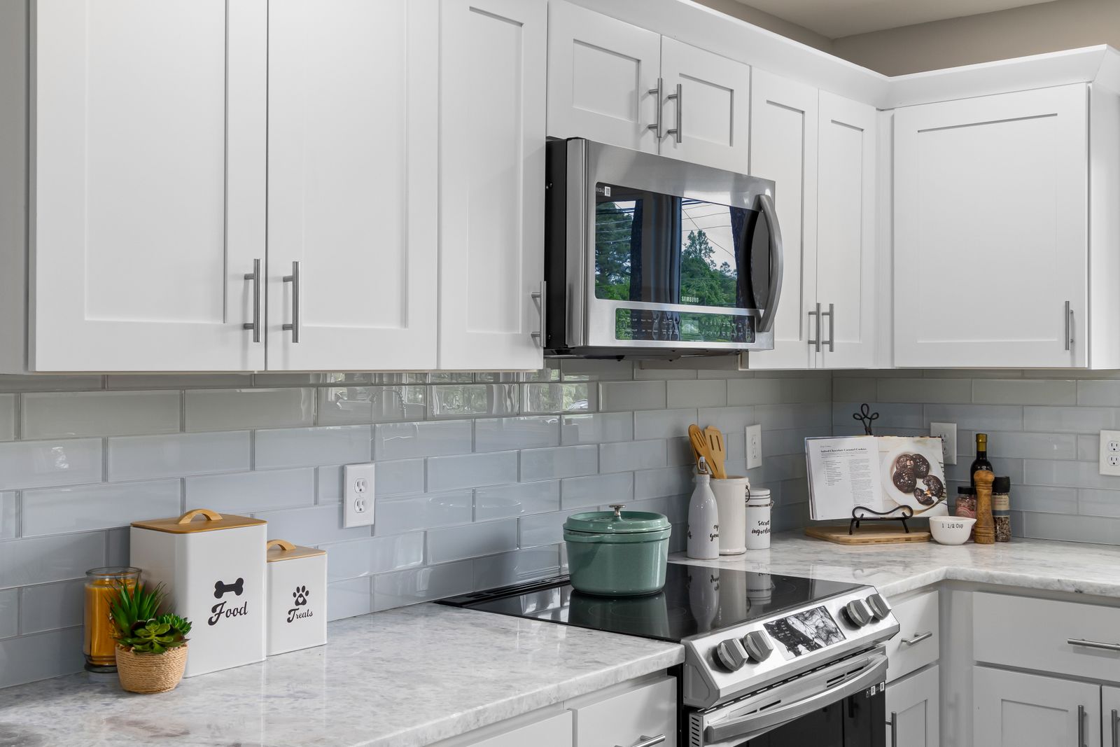 Bright kitchen with white cupboards, tiled backsplash and stone counter