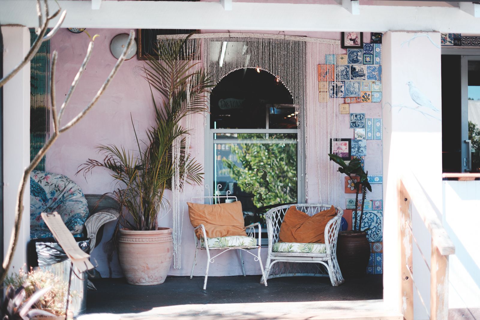 Sunny covered porch with cushioned wicker chairs and potted plants